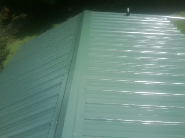 New green metal panels meeting at the ridge of a roof — Flat Roof Repair work by our crew in Semora