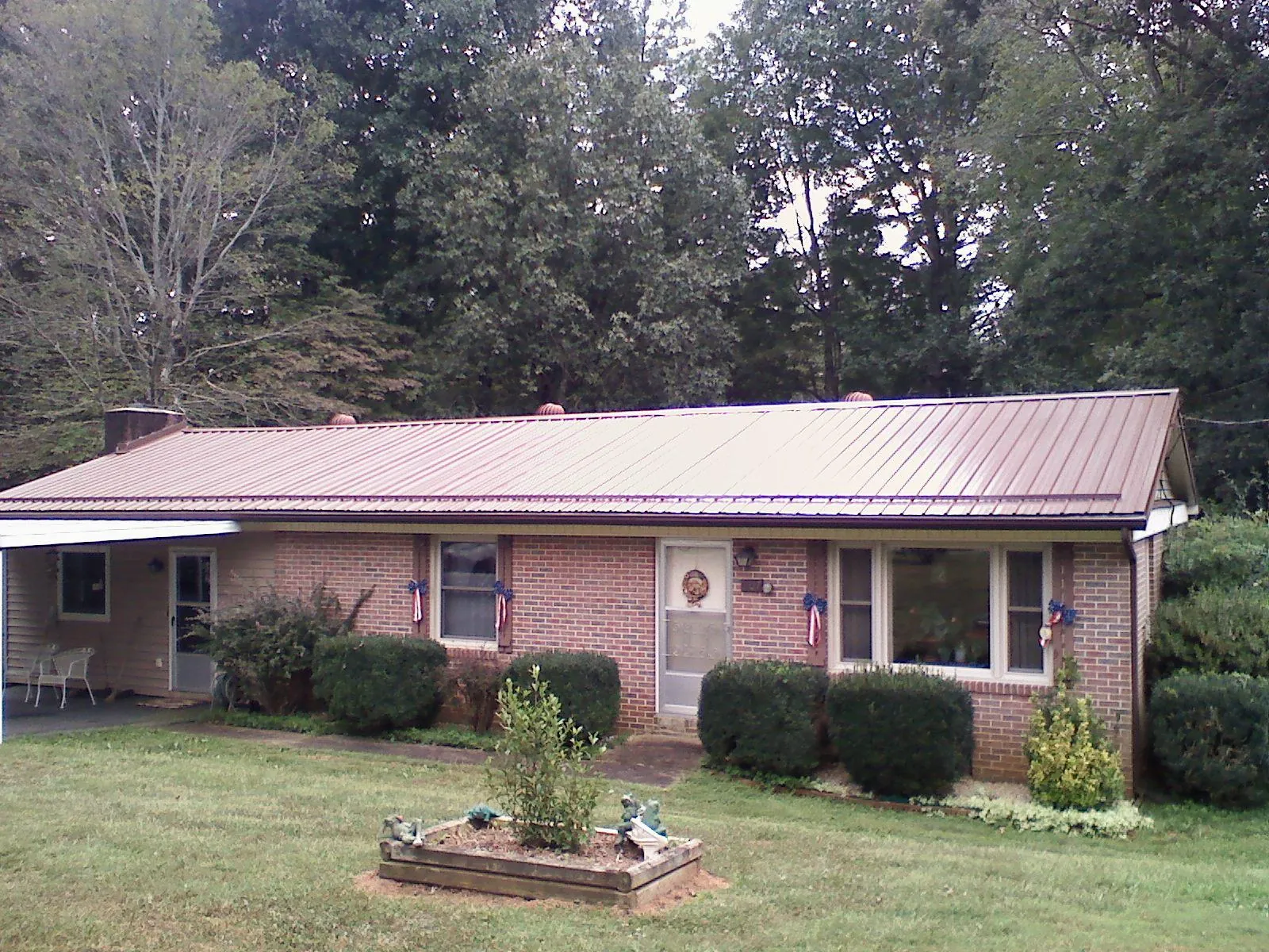Bronze metal roof on a brick ranch home with a carport in Semora