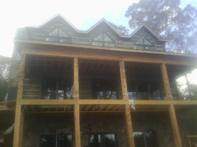 Dormers and porch framing on a large log home under construction — Roof Coating work by our crew in Semora