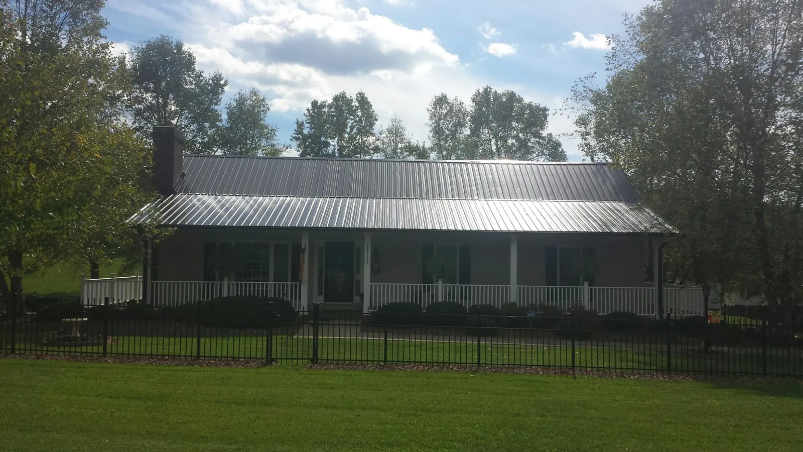 Gray metal roof on a brick ranch with a full width front porch — Gutter Guard Installation work by our crew in Semora